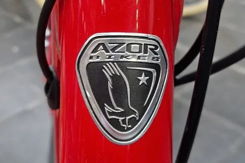 Azor Bikes embossed metal head badge on a red frame